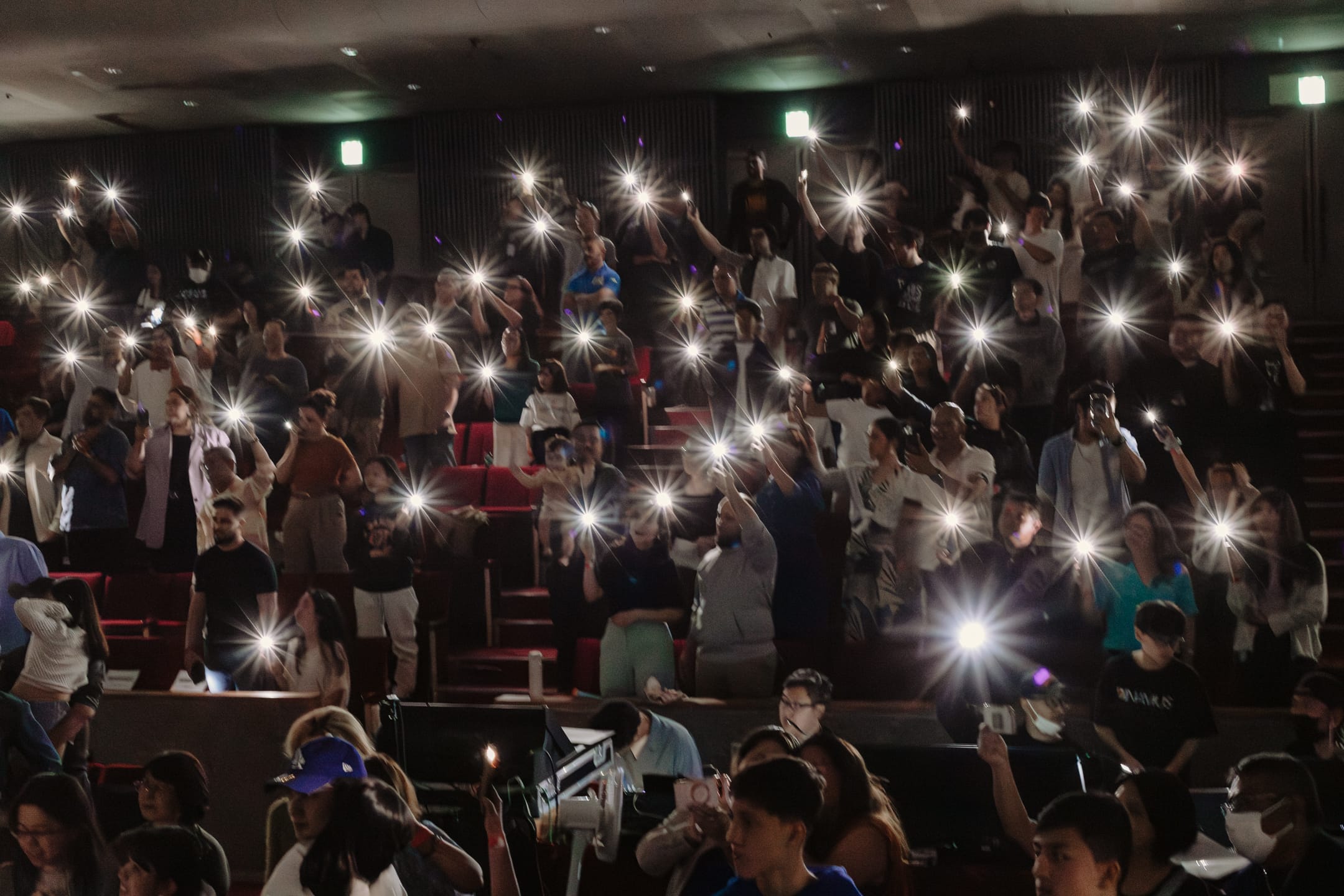 Plateia do recital com celulares erguidos e luzes acesas, em um momento de emoção coletiva